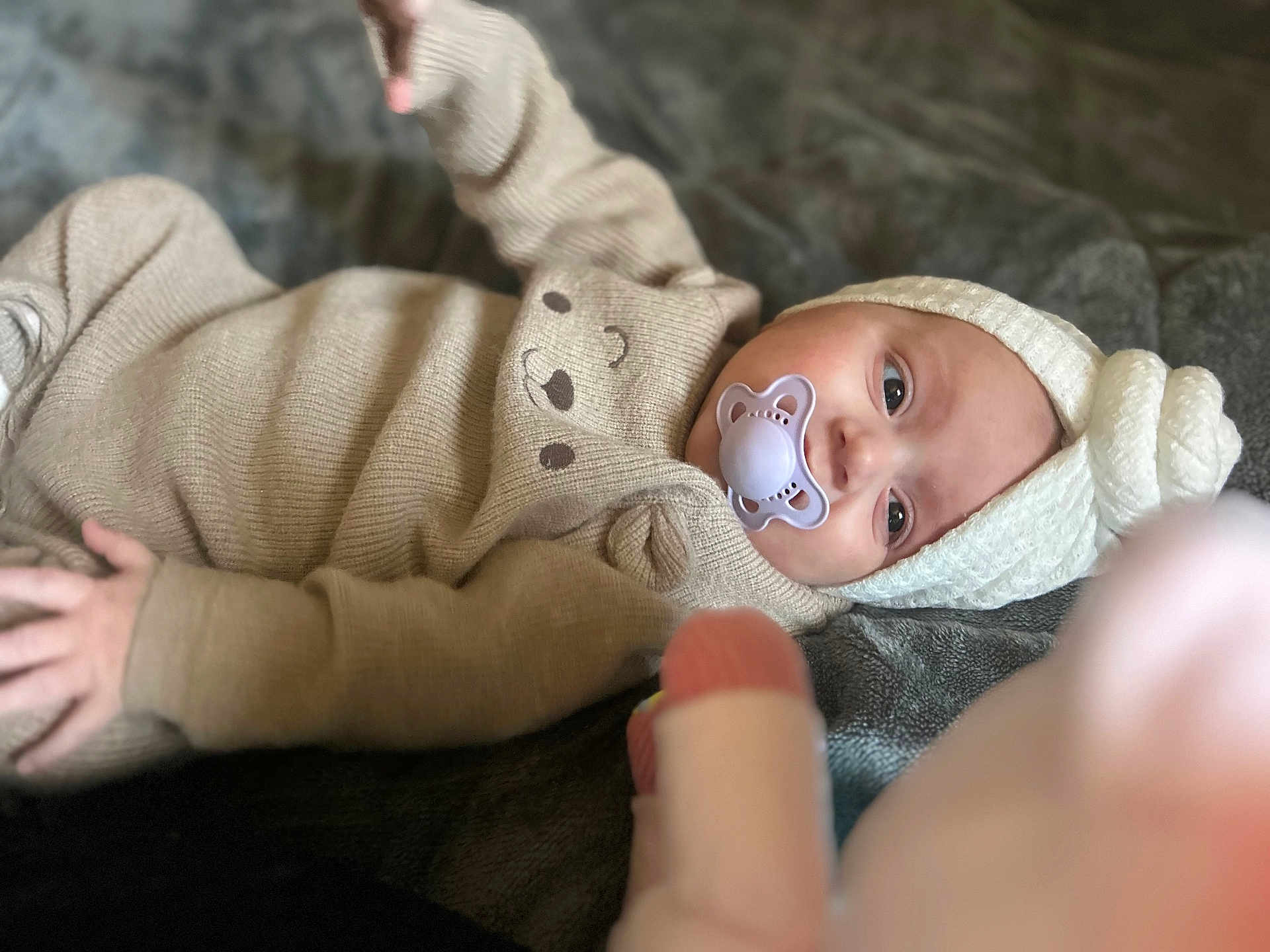 Hanaé a rejoint le concours — aidez-le/la à gagner de superbes lots ! baby, pacifier, knit_hat, knit_outfit, beige_clothing, blanket, infant, child, cute, soft_texture, face, portrait, lying_down, warm_clothing, indoor, headwear, baby_boy, baby_girl, calm, cozy