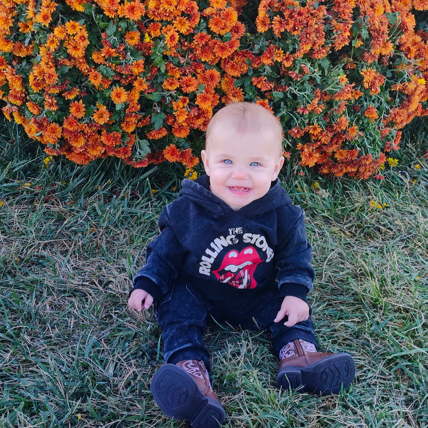 Paisley is registered to the contest to win money with this photo: baby, clothing, daisy, face, flower, footwear, geranium, grass, head, jeans, leaf, pants, person, petal, photography, plant, portrait, shoe, sitting, vegetation