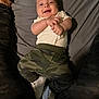 Jayden joined the competition — help win amazing prizes! baby, infant, smile, face, camo_pants, white_shoes, hands, lying_down, fabric, comfort, cute, child, person, apparel, footwear, indoor, happy, expression, small_person, casual_clothing