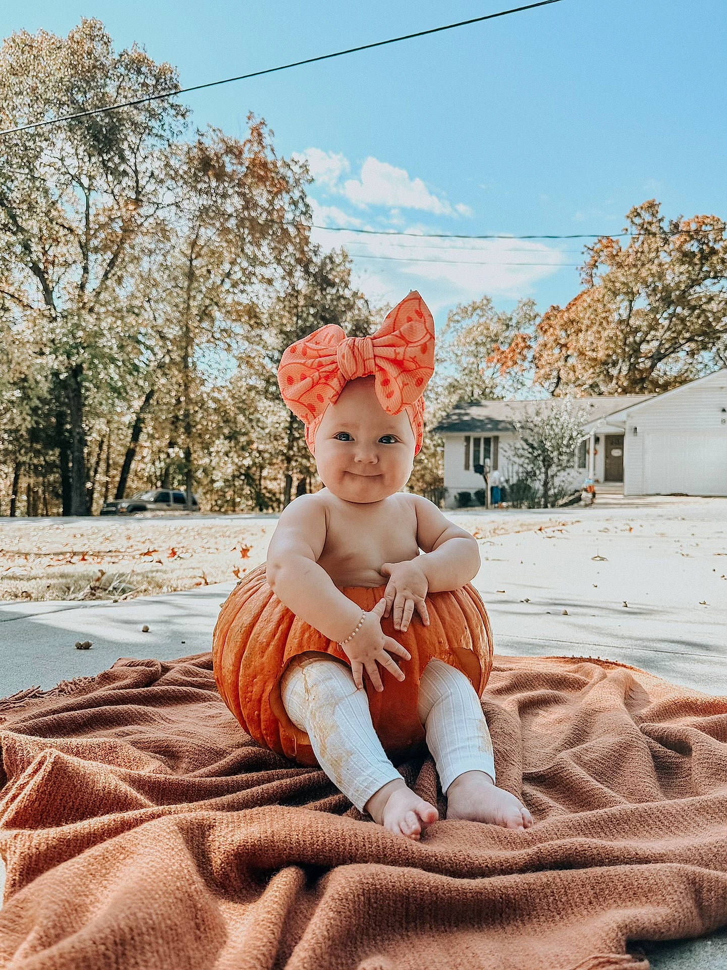 Aurie is registered to the contest to win money with this photo: baby, cloud, fawn, fun, fur, grass, happy, hat, headwear, joy, landscape, leisure, orange, people_in_nature, person, sitting, sky, smile, sun_hat, toddler