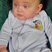 Finlay is registered to the contest to win money with this photo: baby, child, infant, onesie, mickey_mouse, pluto, blue_eyes, couch, cushion, clothing, hand, face, head, person, sitting, indoor, wooden_shelf, soft_texture, cute, portrait