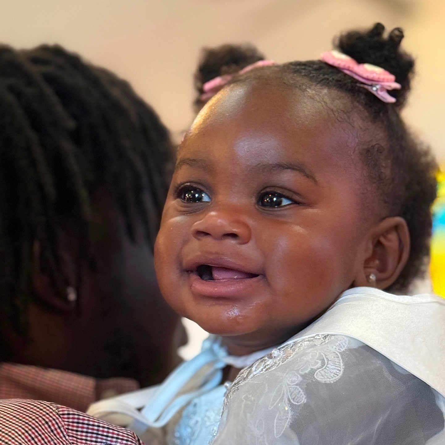 Xyla is registered to the contest to win money with this photo: adult, baby, black_hair, celebration, child, closeup, cute, face, family, hair_clips, hand, happy, holding, indoor, infant, lace, person, portrait, smiling, white_clothing
