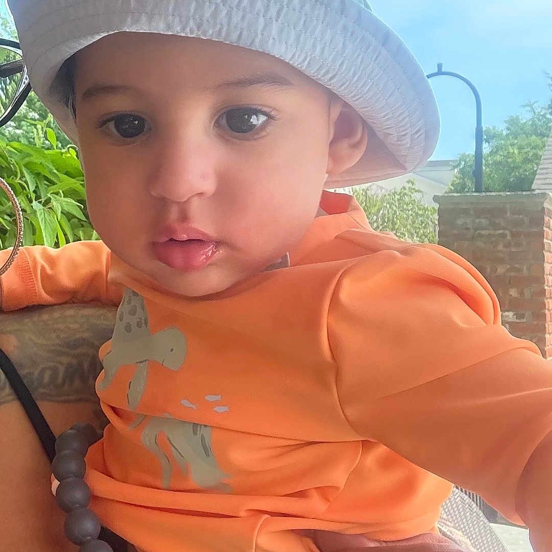 Ralph joined the competition — help win amazing prizes! toddler, baby, child, hat, bucket_hat, orange_shirt, pacifier, hand, red_nail_polish, outdoor, greenery, tree, sky, person, holding, curious, casual_clothing, daylight, portrait, cute