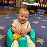 Isabella is registered to the contest to win money with this photo: baby, child, smiling, indoor, carpet, baby_seat, toy, crib, floor, playroom, happy, infant, childcare, furniture, colorful, person, toddler, clothing, footwear, room