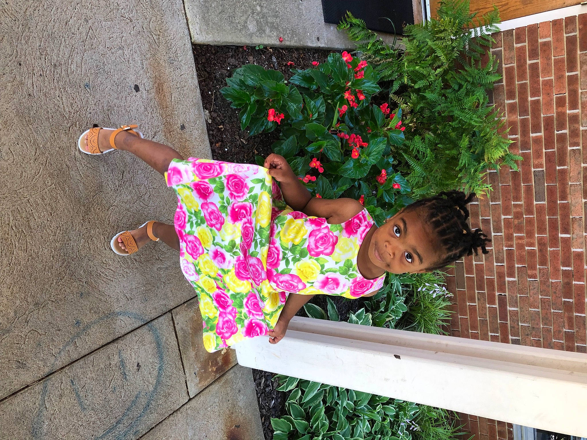 Zari Satchell is registered to the contest to win money with this photo: annual_plant, brick, brickwork, flower, flowerpot, grass, green, house, houseplant, human_leg, leaf, leisure, magenta, person, plant, sandal, sitting, thigh, toddler, window