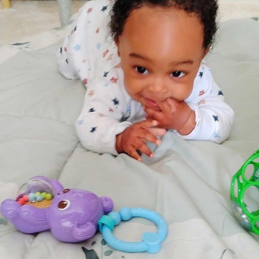 Bryan a rejoint le concours — aidez-le/la à gagner de superbes lots ! baby, infant, toy, play_mat, plush_toy, elephant_toy, giraffe_toy, hand, face, curly_hair, floor, carpet, white_clothing, patterned_clothing, indoor, child, cute, smiling, playtime, soft_toys