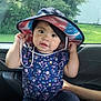 bucket_hat, building, car_interior, casual, child, clothing, curious_expression, daylight, floral_shirt, greenery, hat, holding, person, playing, portrait, sitting, supporting_arm, toddler, trees, window