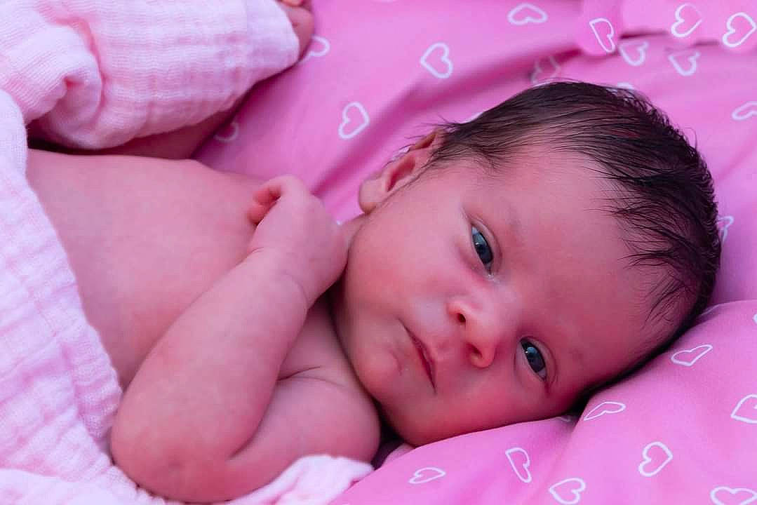 Emily is registered to the contest to win money with this photo: baby, baby_toddler_clothing, cheek, child, comfort, eye, eyebrow, eyelash, face, hair, happy, head, linens, lip, magenta, nose, person, pink, skin, textile