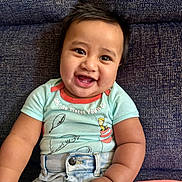 Matthew is registered to the contest to win money with this photo: baby, child, smiling, happy, sitting, denim, clothing, shirt, couch, indoor, portrait, cute, infant, face, person, young_child, joy, casual, blue, textile
