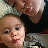 child, toddler, woman, selfie, puckered_lips, mickey_mouse, sweatshirt, indoor, face, portrait, cute, playful, person, holding_object, casual_clothing, close_up, skin, hair, seated, fun