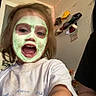 Leilani is registered to the contest to win money with this photo: child, face_mask, happy, smiling, selfie, indoor, childrens_clothing, drawing, hat, fairy_lights, wall, person, mouth_open, hair, white_shirt, fun, playful, young_child, expression, room
