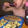 toddler, child, eating, food, spoon, plate, cereal, oatmeal, sippy_cup, table, indoor, person, meal, breakfast, colorful, happy, young_child, feeding, kitchen, dining