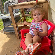 Leilani is registered to the contest to win money with this photo: toddler, child, red_chair, plastic_chair, sandals, outdoor, porch, wooden_chair, high_chair, snacks, sock, sunlight, trees, greenery, clothing, person, playful, relaxed, summer, casual