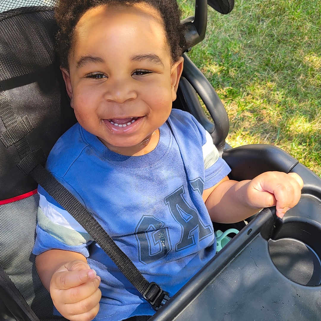 Odrian is registered to the contest to win money with this photo: baby, bodypart, car, clothing, face, finger, grass, hand, happy, head, nature, outdoors, park, person, photography, plant, portrait, smile, stroller, t_shirt