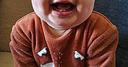 Soën a rejoint le concours — aidez-le/la à gagner de superbes lots ! baby, big_eyes, chubby_cheeks, close_up, couch, feet, fox_design, furniture, hands, home, indoor, infant, joyful, onesie, orange_clothing, portrait, rosy_cheeks, sitting, smiling, tooth