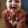 baby, infant, smiling, chubby_cheeks, tooth, onesie, fox_design, orange_clothing, couch, sitting, portrait, close_up, big_eyes, joyful, indoor, home, furniture, hands, feet, rosy_cheeks