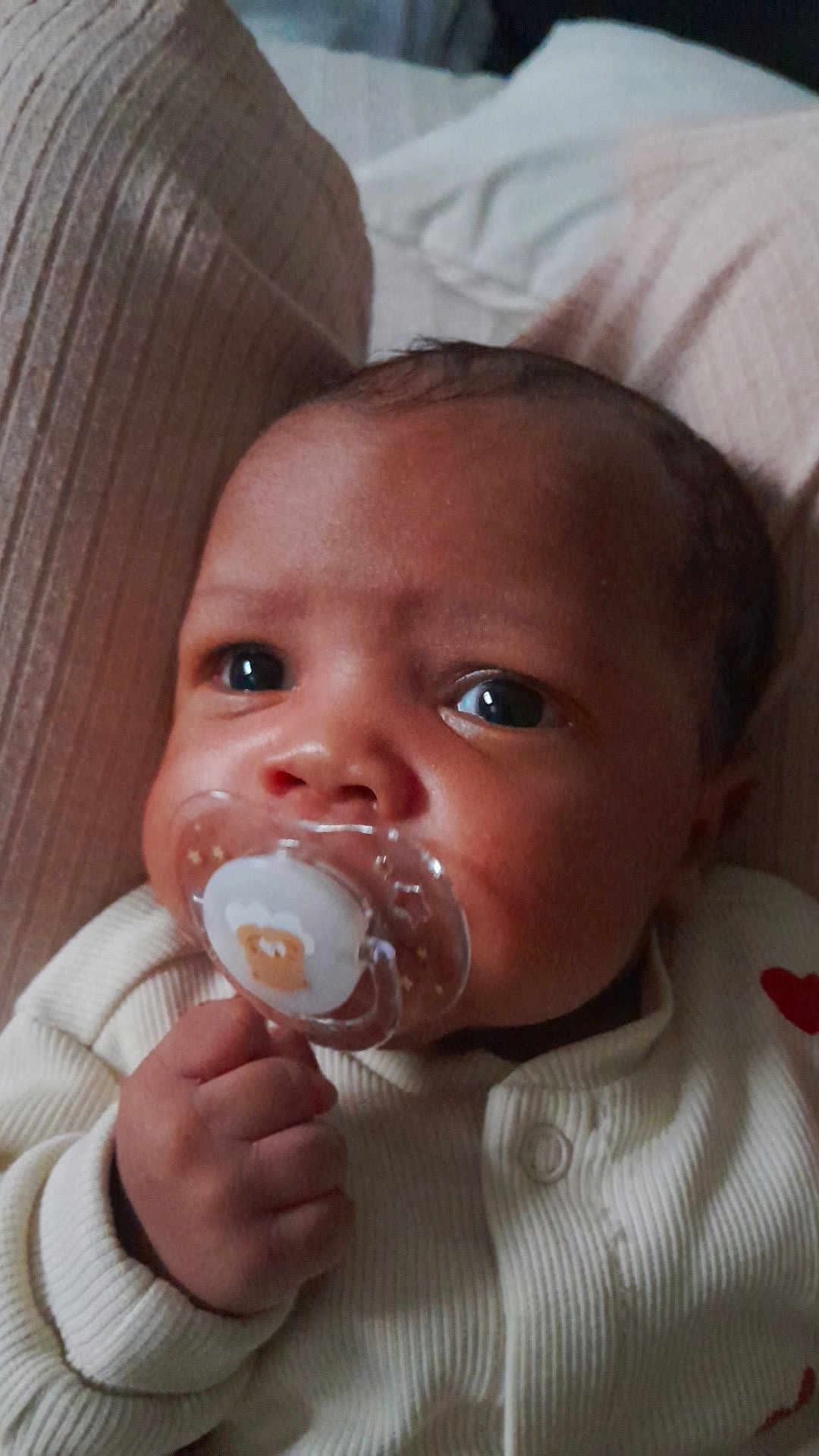 Yoni a rejoint le concours — aidez-le/la à gagner de superbes lots ! baby, pacifier, hand, face, infant, cushion, clothing, onesie, closeup, portrait, indoor, sleeping_area, cute, newborn, skin, expression, resting, child, young, comfort