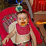 baby, bib, child, clothing, curtain, diaper, fabric, face, feeding, floor, food, happy, high_chair, indoor, messy, plant, seat, smile, spoon, toy