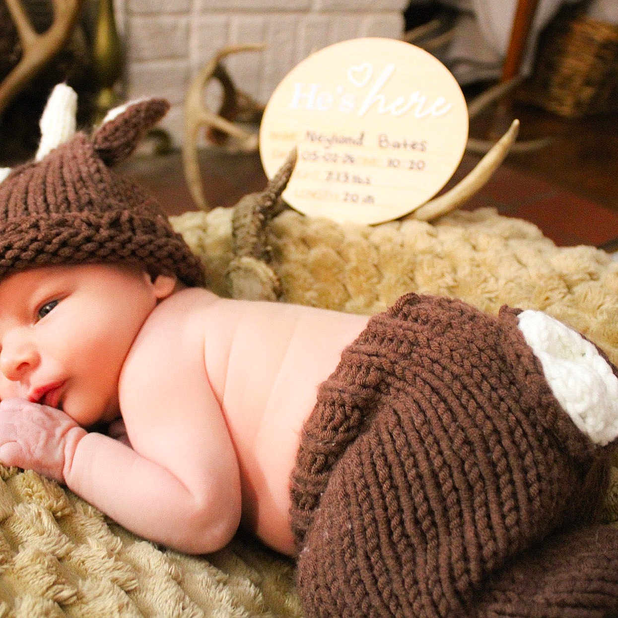 Neyland joined the competition — help win amazing prizes! baby, newborn, infant, knit_hat, knit_pants, brown_clothing, blanket, soft_texture, lying_down, antlers, wooden_sign, decor, indoor, resting, cute, peaceful, portrait, child, newborn_photography, cozy
