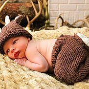 Neyland joined the competition — help win amazing prizes! baby, infant, knit_hat, knit_pants, antlers, blanket, lying_down, face, skin, newborn, cute, soft_texture, indoors, warm_colors, portrait, baby_clothing, resting, cozy, headwear, decor