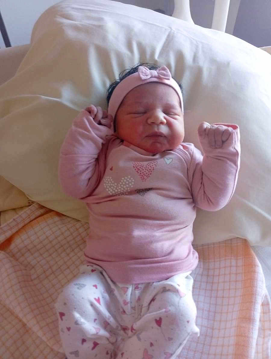 Mia participe au concours pour gagner de l'argent avec cette photo : baby, newborn, infant, pink_clothing, headband, sleeping, pillow, blanket, bed, cute, peaceful, small_hands, lying_down, indoors, soft_lighting, heart_patterns, cozy, child, person, toddler