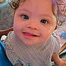 Eliana is registered to the contest to win money with this photo: baby, child, curly_hair, blue_eyes, smile, face, portrait, close_up, infant, cute, clothing, texture, person, indoors, happy, young_child, holding, warm_lighting, soft_focus, background_blur
