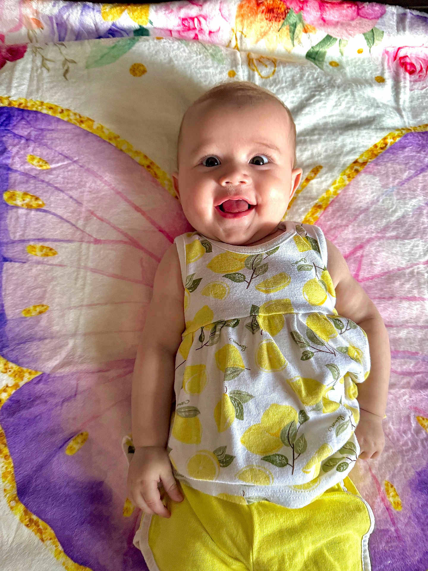 Inaya joined the competition — help win amazing prizes! baby, smiling, infant, child, blanket, butterfly_wings, clothing, yellow, white, patterned, happy, cute, face, portrait, lying_down, playful, indoors, skin, head, cheerful