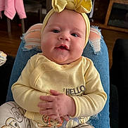 Inaya joined the competition — help win amazing prizes! baby, child, infant, yellow_clothing, headband, hands, sitting, lap, indoor, furniture, jeans, ripped_jeans, cute, smiling, person, face, portrait, cozy, casual, home