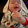 Inaya is registered to the contest to win money with this photo: baby, child, smiling, hood, bunny_ears, onesie, hand, face, indoor, fireplace, warm_light, cozy, patterned_clothing, cute, happy, infant, soft_texture, portrait, expression, playful