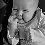baby, infant, smiling, cheeks, hand, bib, clothing, seat, straps, black_and_white, portrait, cute, young_child, expression, cozy, indoor, soft_lighting, face, person, closeup