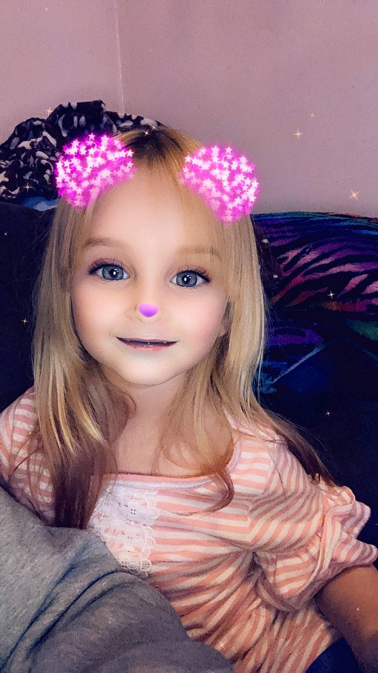 Cheyanne is registered to the contest to win money with this photo: dress, eyebrow, eyelash, flash_photography, fun, hairstyle, happy, head, headband, headpiece, iris, joy, lip, long_hair, party_supply, person, petal, pink, purple, skin