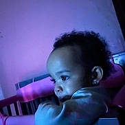 Zaniyah is registered to the contest to win money with this photo: baby, child, crib, pink, blue_light, purple_light, indoor, portrait, curly_hair, earrings, infant, face, looking_away, soft_lighting, close_up, person, cute, thoughtful, young_child, home
