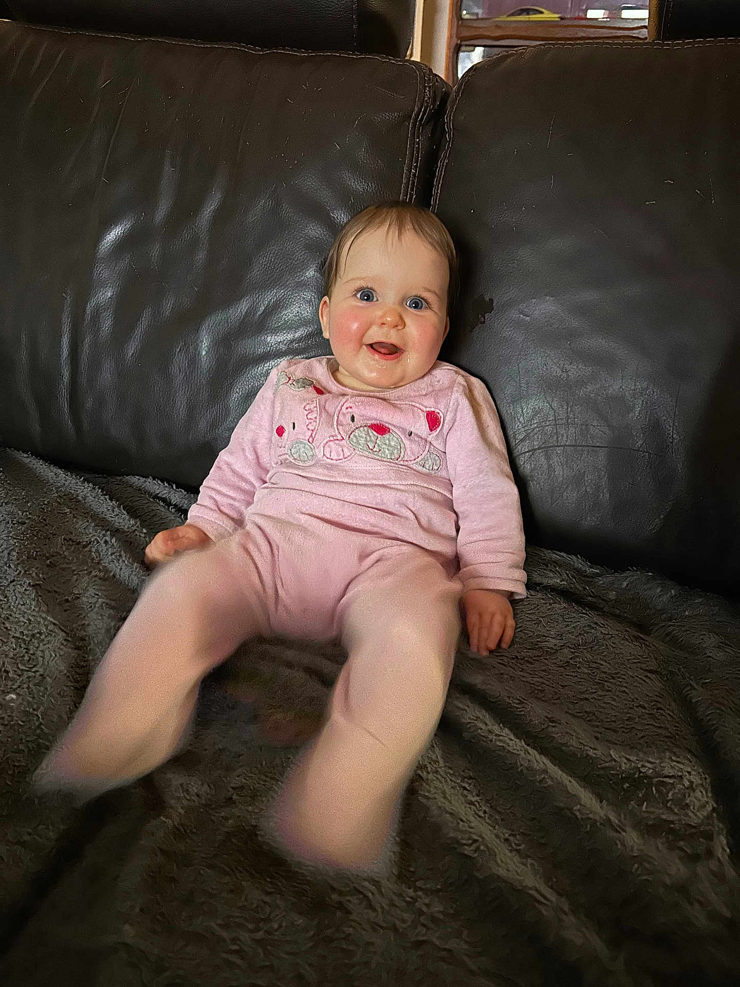 Victoria a rejoint le concours — aidez-le/la à gagner de superbes lots ! baby, child, smiling, pink_clothing, teddy_bear_design, blue_eyes, drool, leather_couch, blanket, indoor, happy, sitting, portrait, young_child, cozy, furniture, person, cute, motion_blur, rosy_cheeks
