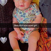 Myabellah joined the competition — help win amazing prizes! baby, child, blue_eyes, headband, flower, onesie, crocheted_shoes, couch, heart_emoji, text_overlay, cute, infant, portrait, smiling, sitting, indoors, person, fabric, colorful, happy