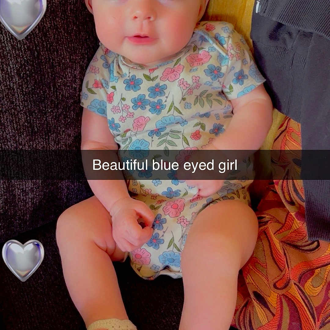 Myabellah joined the competition — help win amazing prizes! baby, child, blue_eyes, headband, flower, onesie, crocheted_shoes, couch, heart_emoji, text_overlay, cute, infant, portrait, smiling, sitting, indoors, person, fabric, colorful, happy