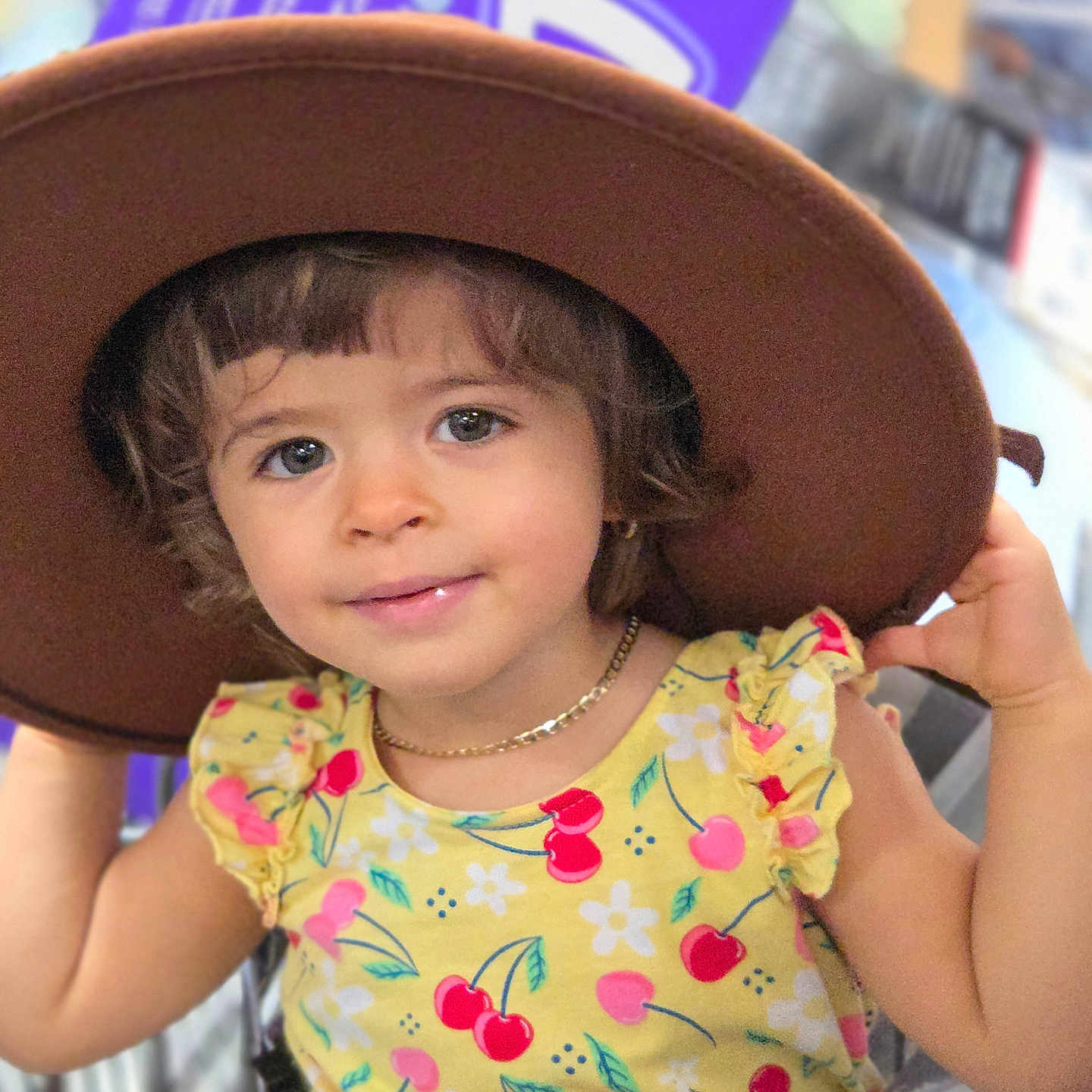 Stephany is registered to the contest to win money with this photo: accessory, apparel, cherry_pattern, child, curly_hair, cute, eyes, face, fashion, hands, hat, holding, indoor, necklace, person, portrait, shopping_cart, smiling, toddler, yellow_dress