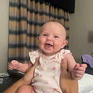 Elizabeth is registered to the contest to win money with this photo: baby, bed, blanket, child, clothing, curtains, cute, furniture, hands, happy, holding, indoor, infant, onesie, person, portrait, room, skin, smiling, socks