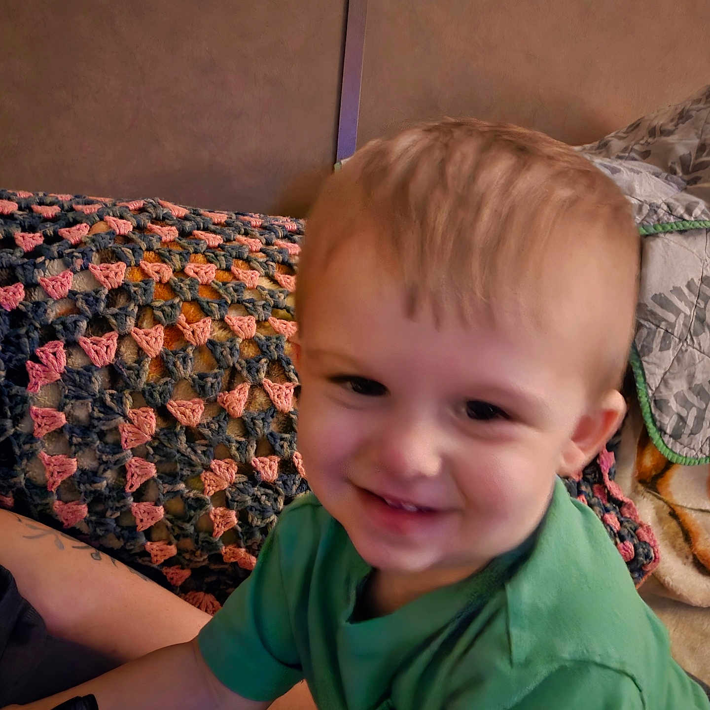 Sawyer is registered to the contest to win money with this photo: blanket, child, comfort, couch, crocheted_blanket, face, furniture, green_shirt, hair, happy, home, indoor, person, play, relaxed, sitting, skin, smiling, toddler, toy_car