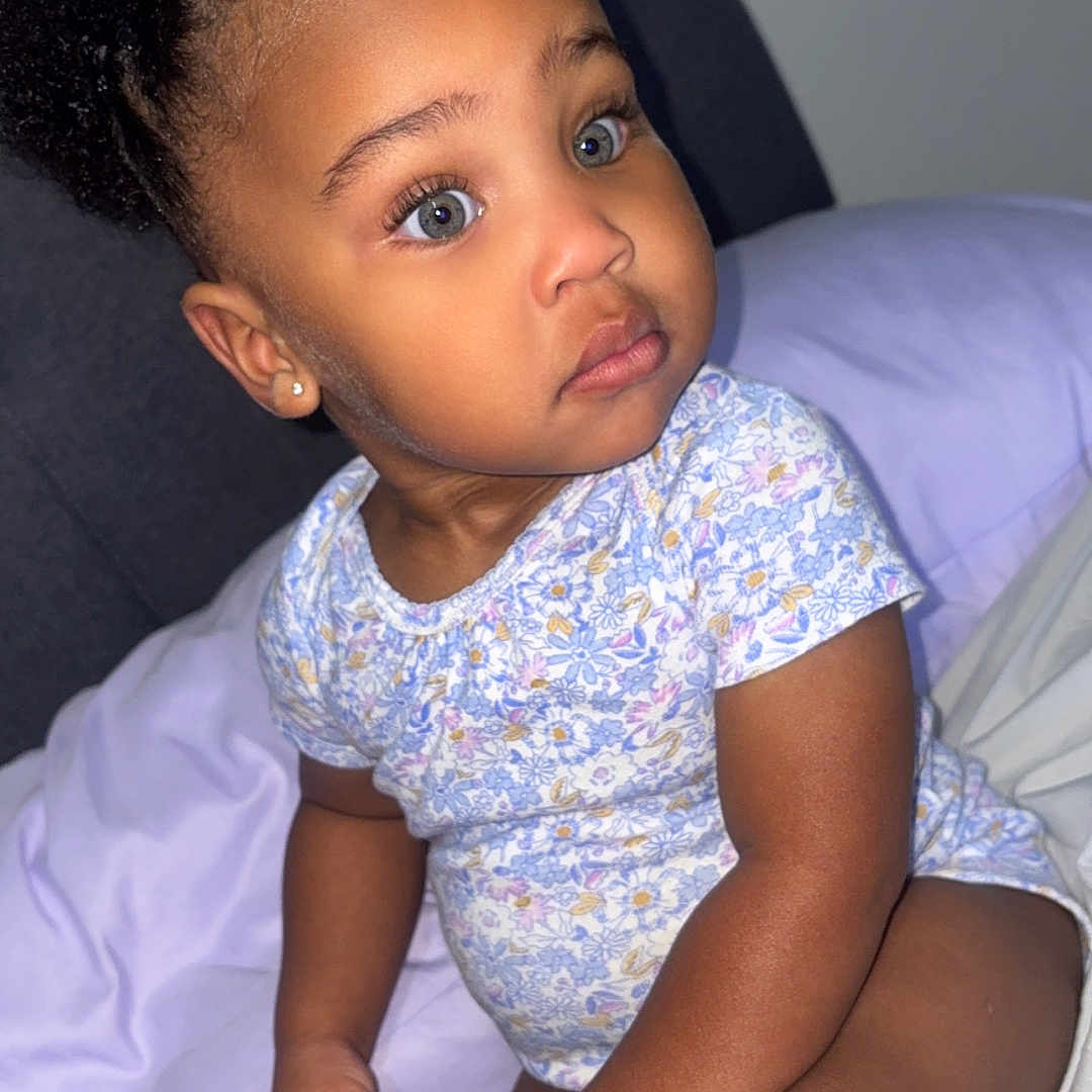 Cimani joined the competition — help win amazing prizes! toddler, child, blue_eyes, braided_hair, bed, bedding, pajamas, curious, indoor, portrait, cute, young_child, skin, person, sitting, hand, face, infant, clothing, home