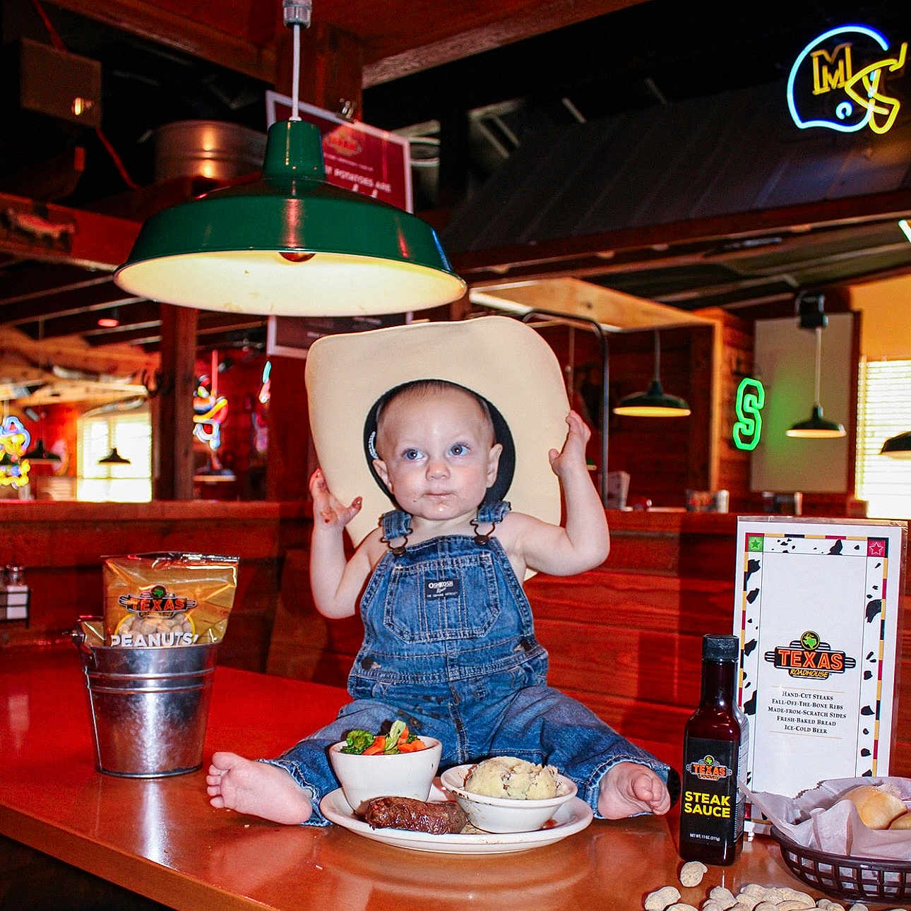 Jaxsin joined the competition — help win amazing prizes! barefoot, bucket, child, cowboy_hat, curious, denim_overalls, food, lamp, mashed_potatoes, menu, neon_sign, peanuts, restaurant, seated, steak, steak_sauce, table, toddler, vegetables, wooden_interior
