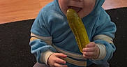 Jaxsin joined the competition — help win amazing prizes! baby, blue_clothing, carpet, casual, child, cute, eating, floor, happy, home, hoodie, indoor, infant, person, pickle, playful, sitting, smiling, socks, wooden_floor