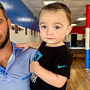Benjamin joined the competition — help win amazing prizes! adult, basketball_graphic, black_tshirt, blue_pants, casual_clothing, child, colorful_background, curly_hair, expression, face, holding, indoor, looking_at_camera, nike_logo, person, pillar, portrait, short_hair, toddler, wood_floor
