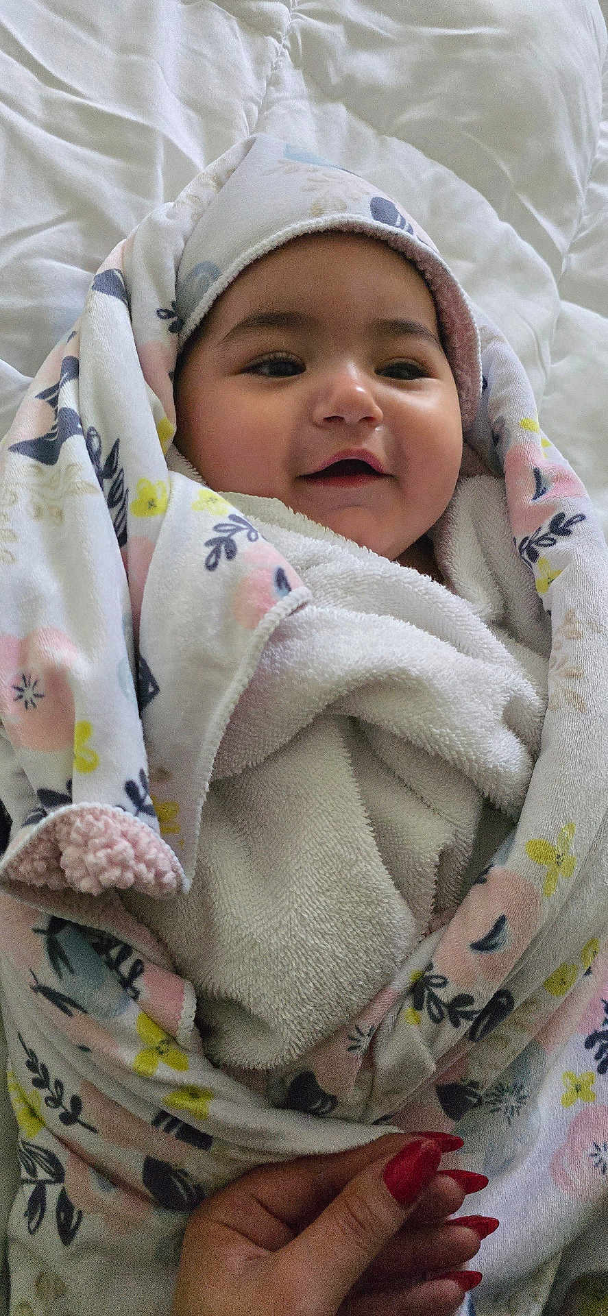 Heaven joined the competition — help win amazing prizes! baby, smiling, blanket, towel, hand, red_nails, floral_pattern, wrapped, cozy, cute, infant, portrait, indoors, soft_texture, happy, child, person, fabric, bed, comfort