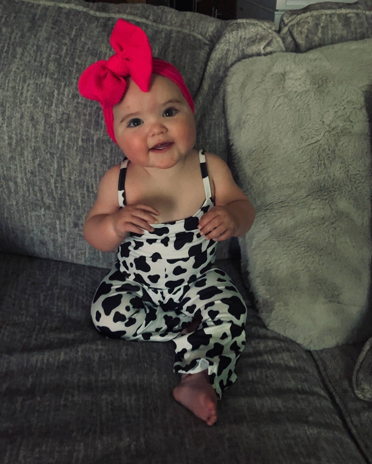 Ila is registered to the contest to win money with this photo: baby, baby_toddler_clothing, cap, comfort, costume_hat, couch, day_dress, dress, foot, fun, happy, head, headwear, human_leg, joy, pattern, person, pink, skin, sleeve