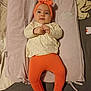 Lia participe au concours pour gagner de l'argent avec cette photo : baby, infant, lying_down, headband, orange_clothing, cream_clothing, baby_mat, butterfly_embroidery, cloud_embroidery, soft_fabric, hands_clasped, white_socks, indoor, bed, cute, calm, child, person, smiling, head