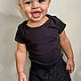 Mase joined the competition — help win amazing prizes! toddler, child, smiling, standing, curly_hair, black_shirt, black_shorts, white_socks, indoor, carpet, wall, happy, cute, person, young_child, portrait, casual_clothing, feet, full_body, light_background