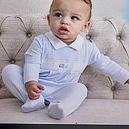 Mase is registered to the contest to win money with this photo: toddler, child, baby, blue_outfit, couch, tufted_furniture, curly_hair, studio_equipment, indoor, portrait, sitting, clothing, expression, cute, person, photography, face, hand, footwear, background