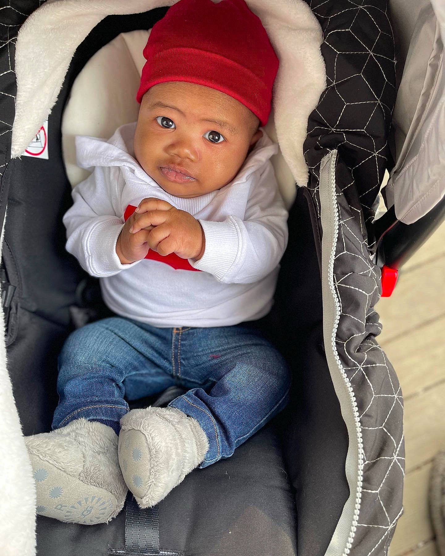 Hezekiah is registered to the contest to win money with this photo: baby, baby_carriage, baby_toddler_clothing, beauty, cap, car_seat, cheek, clothing, comfort, denim, headgear, headwear, jeans, lap, lip, mouth, person, sleeve, textile, toddler