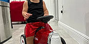 Cyphyr Pineda is registered to the contest to win money with this photo: toddler, child, toy_car, indoor, floor, black_tank_top, red_shorts, socks, smiling, happy, modern_home, television, furniture, tile_floor, wheels, steering_wheel, play, cute, young_child, expression