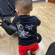 Cyphyr Pineda joined the competition — help win amazing prizes! toddler, child, back_view, black_tshirt, red_shorts, sneakers, stroller, indoor, wood_floor, haircut, person, standing, casual_clothing, flooring, footwear, young_child, baby, small_child, clothing, interior